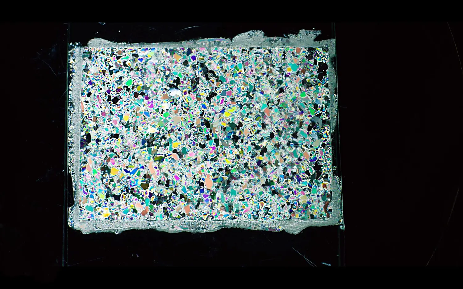 The abstract colors and shapes of an ice core sample viewed through petrographic lens