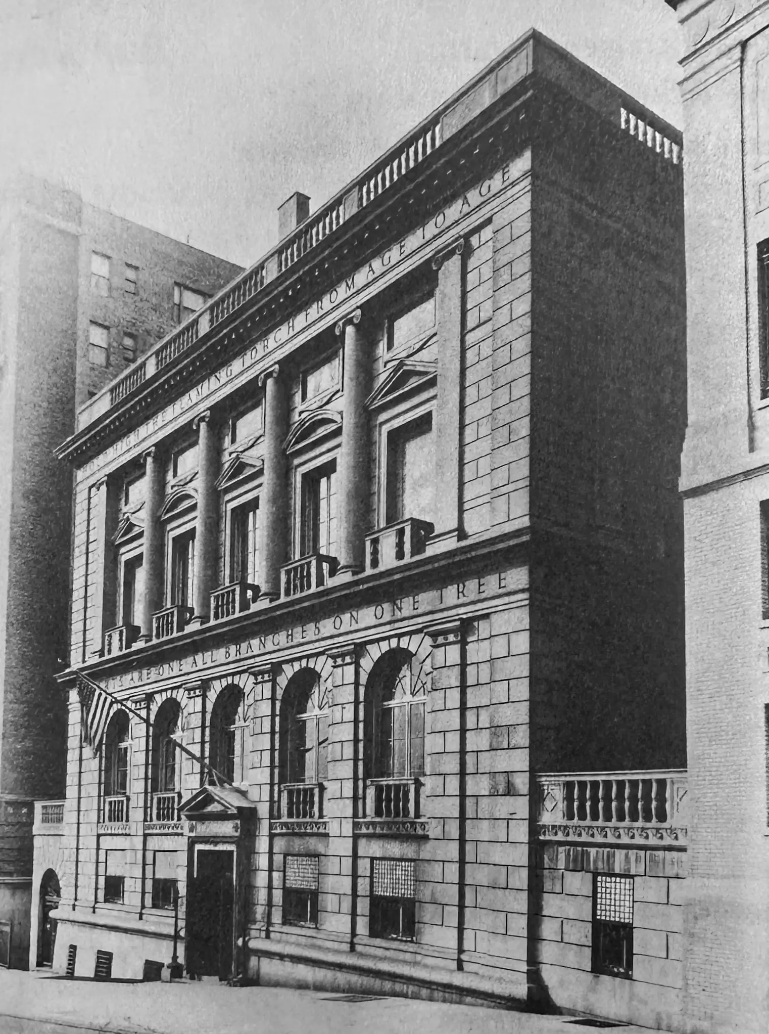 A black and white photograph shows the exterior of the American Academy of Arts and Letters. An American flag hangs above the entrance and there is a partially legible inscription on the building.