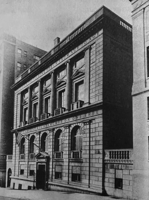 A black and white photograph shows the exterior of the American Academy of Arts and Letters. An American flag hangs above the entrance and there is a partially legible inscription on the building.
