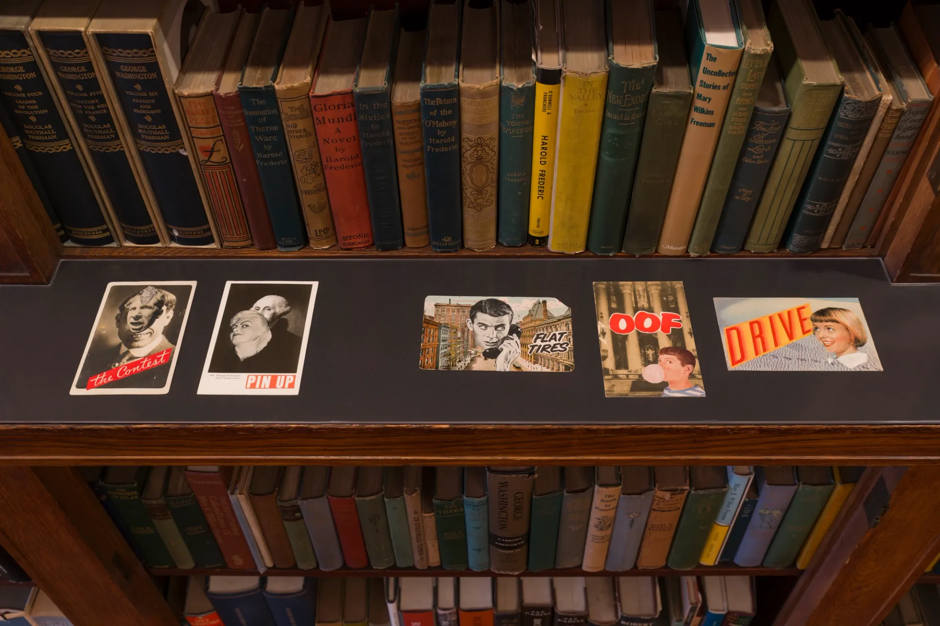 Postcard-sized collages along a bookshelf ledge
