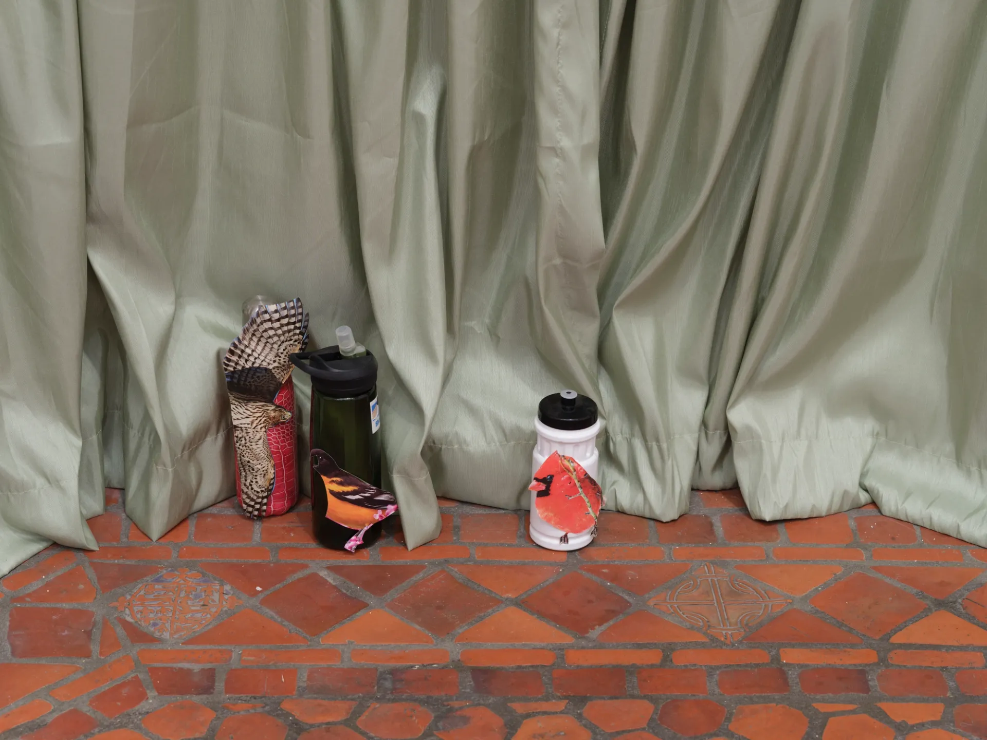 Water bottles in front of green curtain.