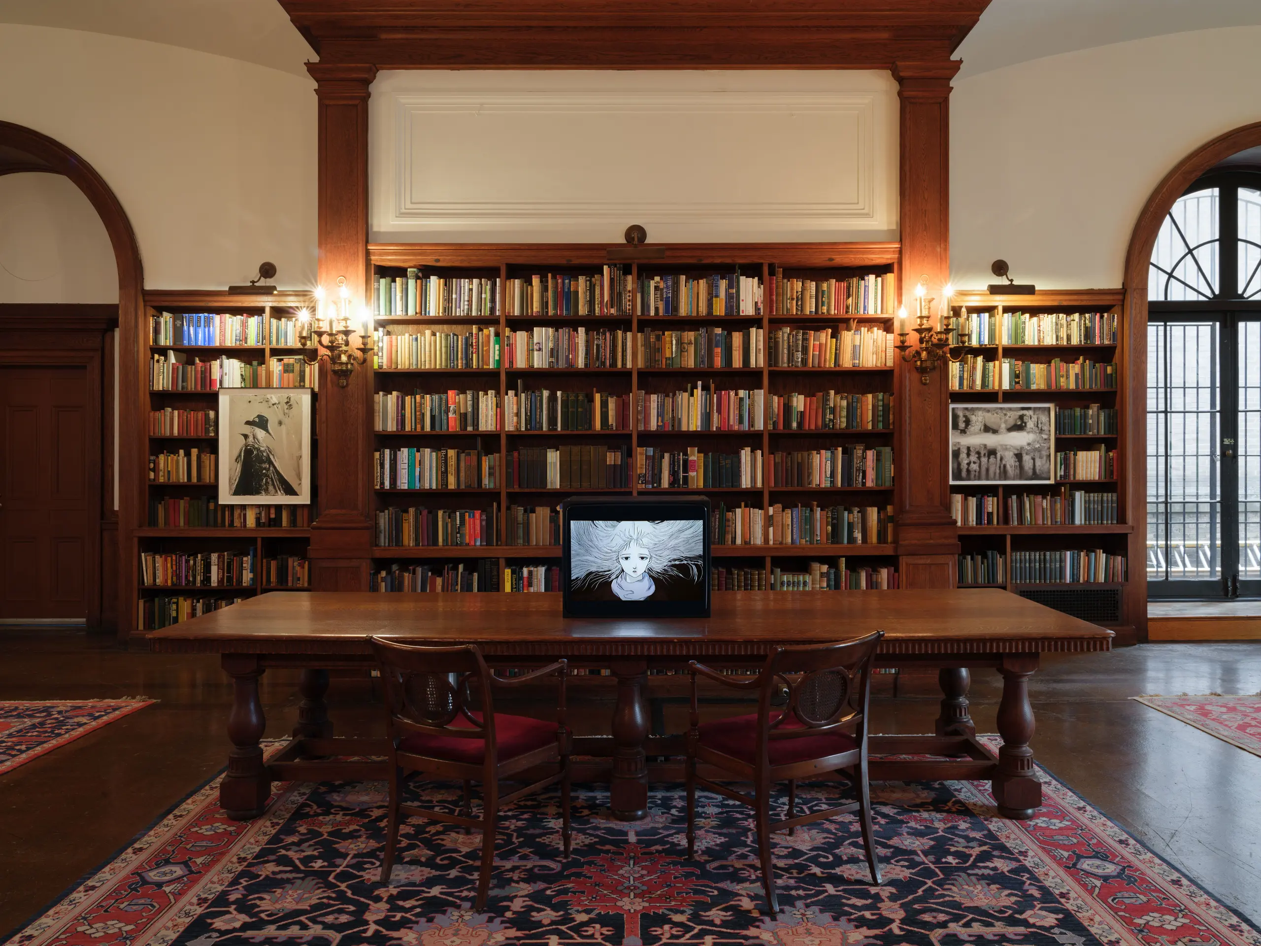 Video monitor and framed artworks in wood-paneled Library