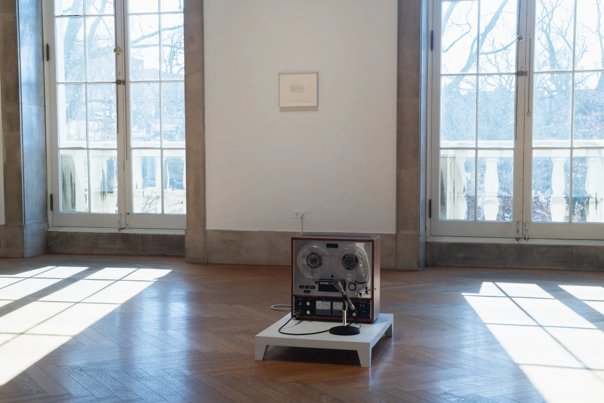 A reel-to-reel tape recorder sits on a wooden plinth