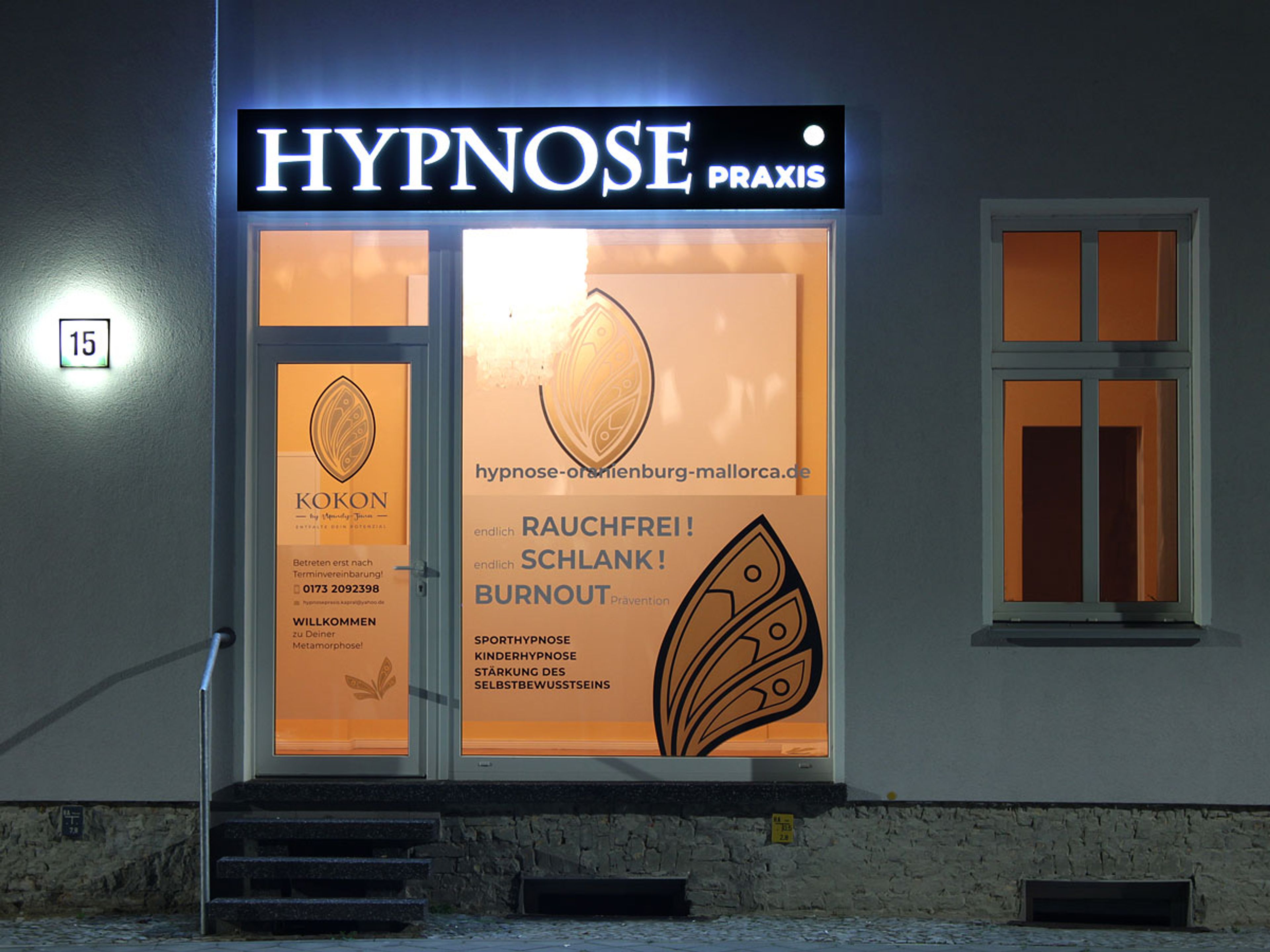 Leuchtkasten über einem Fenster im Erdgeschoss am Abend