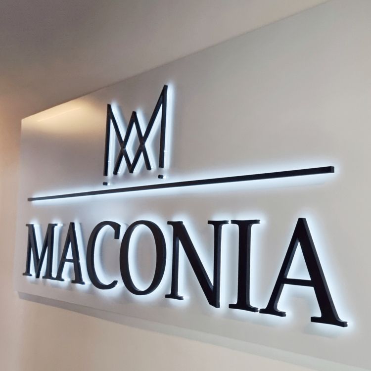 Logo mit Krone und Schriftzug mit hellem Lichtschein an einer weißen Wand