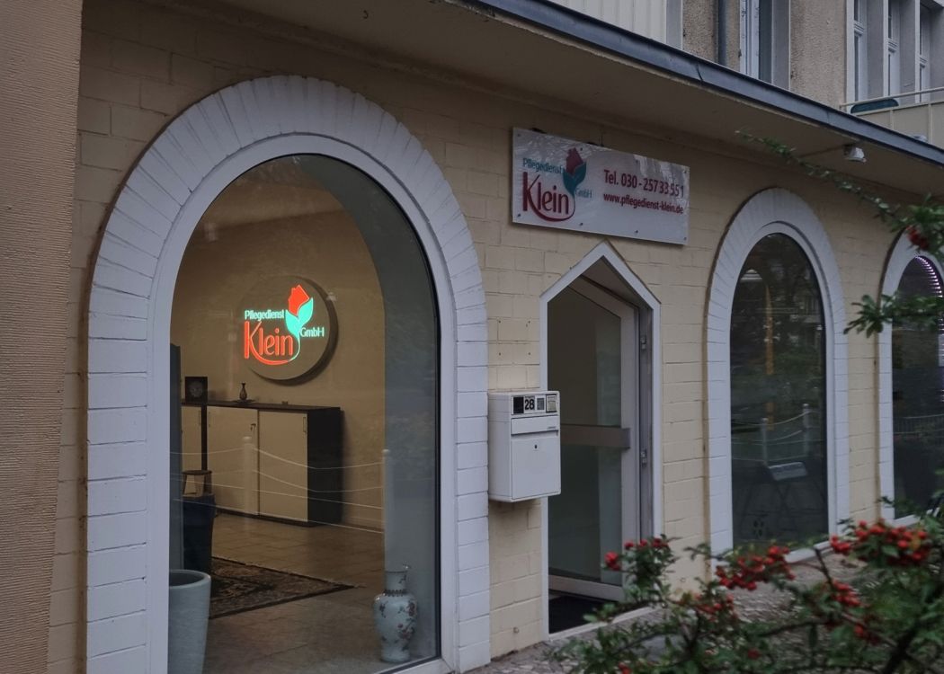 Blick durch ein Rundbogenfenster auf ein rundes, beleuchtetes Logo an der Innenwand, daneben ein Schild an der Fassade