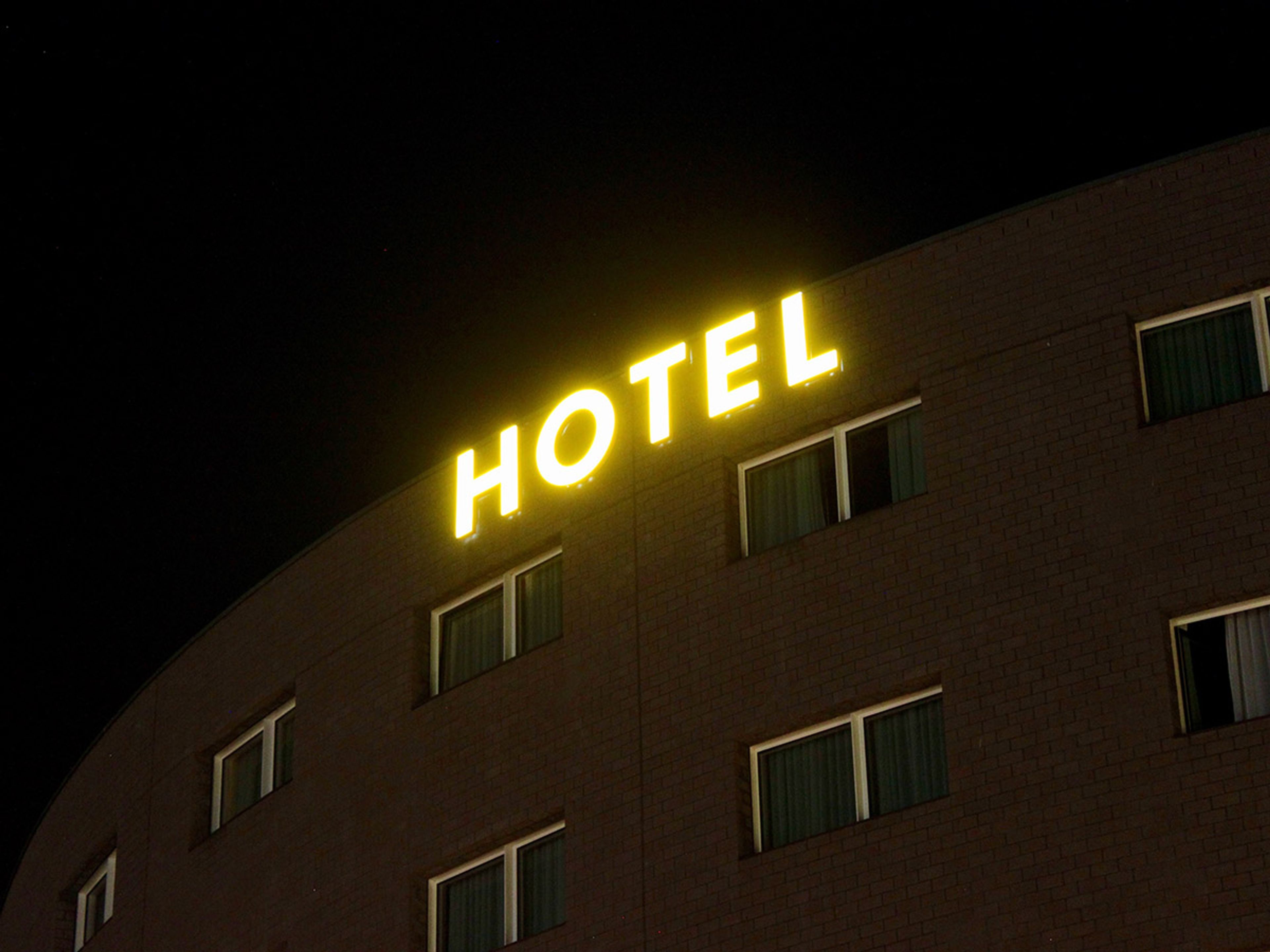 Gelbe Leuchtbuchstaben oben an einem Hotelgebäude bei Nacht