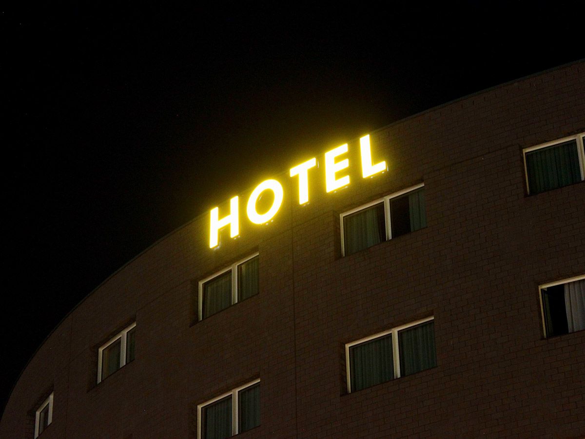 Gelbe Leuchtbuchstaben oben an einem Hotelgebäude bei Nacht