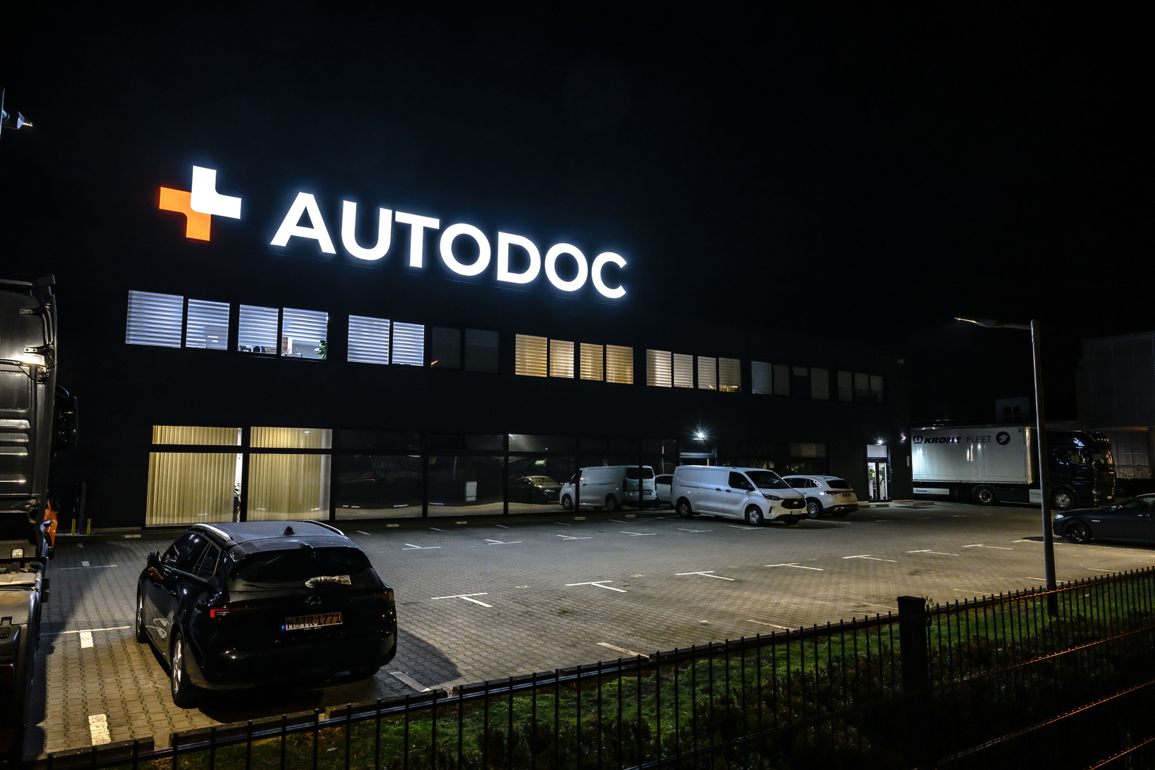 Leuchtbuchstaben mit Logo oben auf einem Firmengebäude bei Nacht
