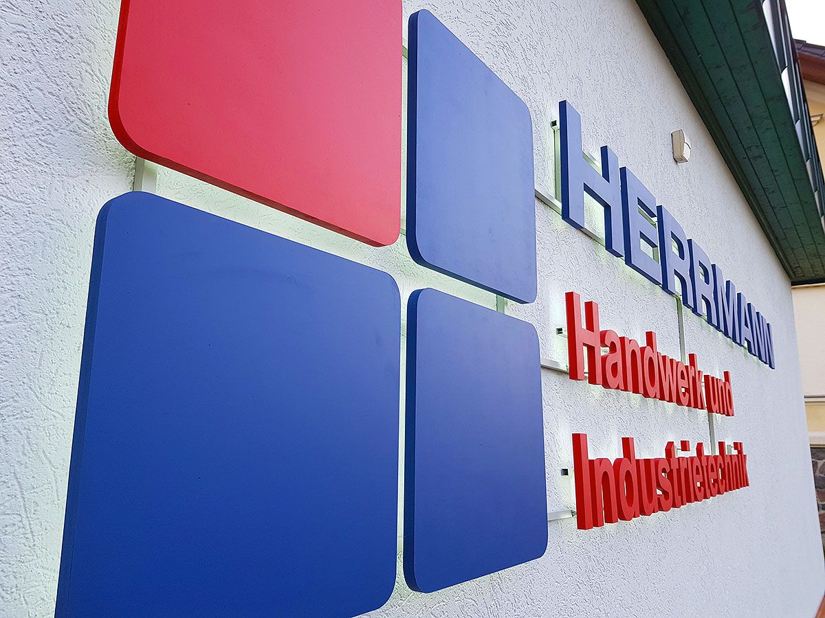 Großes Logo aus roten und blauen Flächen mit Buchstaben an einer hellen Fassade