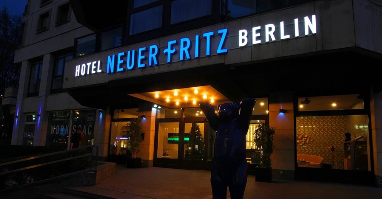 Beleuchteter Schriftzug Hotel Neuer Fritz Berlin über dem Hoteleingang am Abend