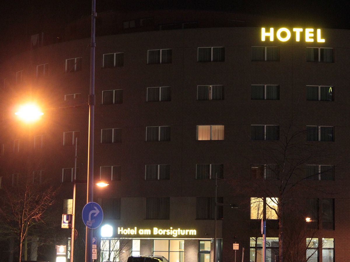 Gelbe Leuchtbuchstaben oben auf einem mehrstöckigen Gebäude am Abend