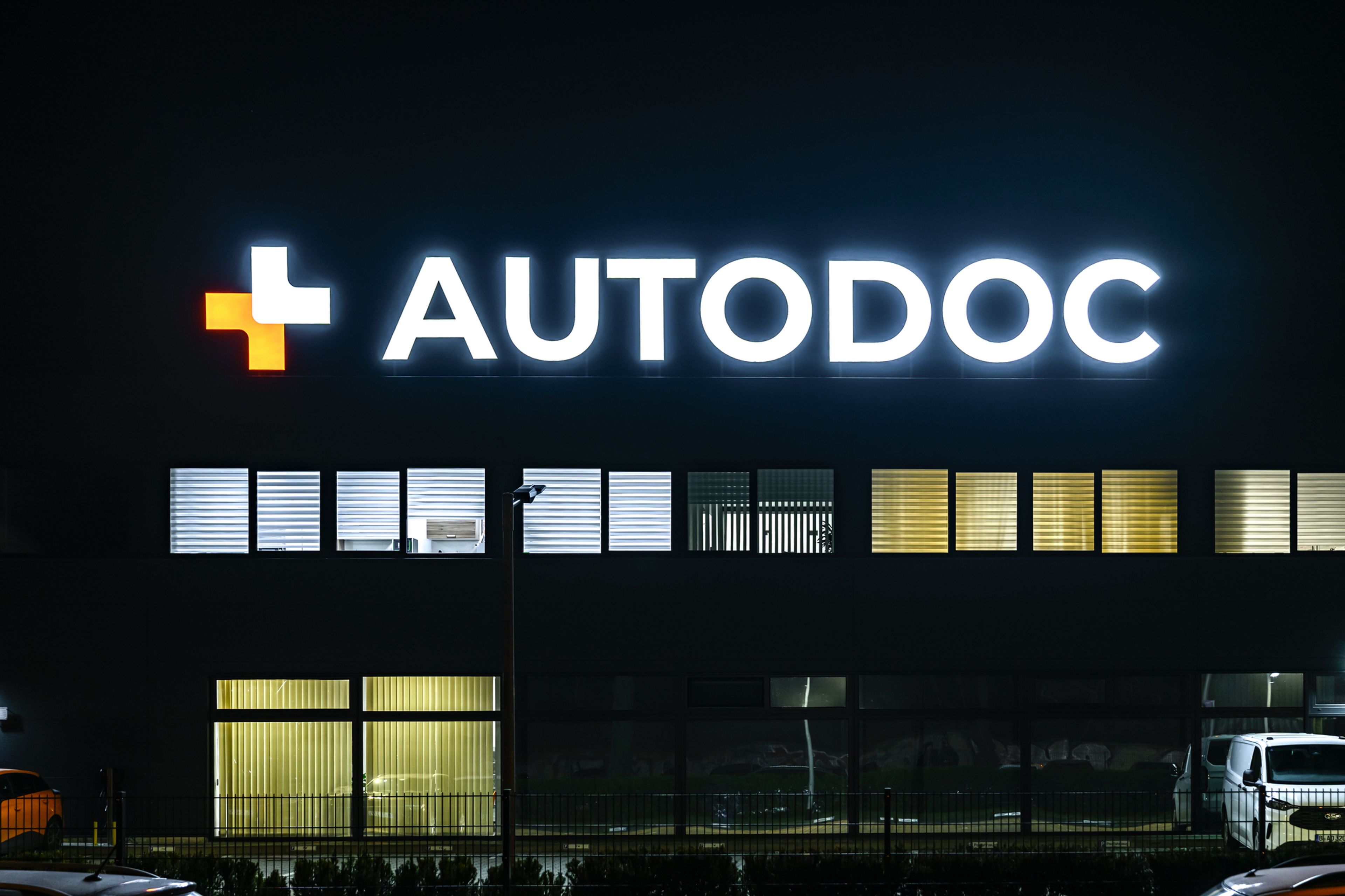 Leuchtbuchstaben mit Logo oben auf einer Firmenhalle bei Nacht
