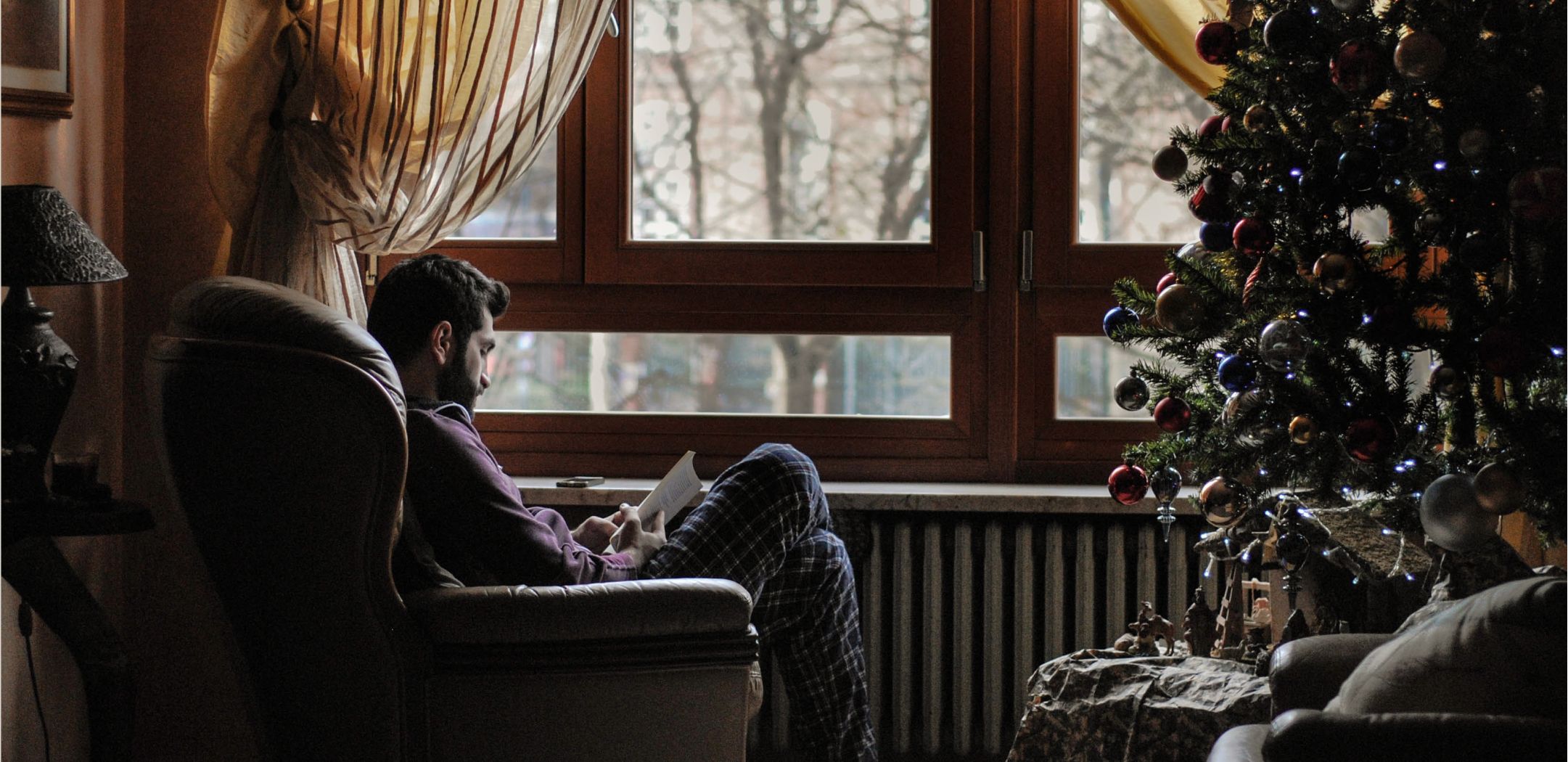 Man sitting in chair near window in a house with holiday decorations