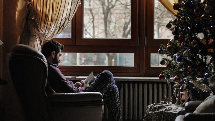 Man sitting in chair near window in a house with holiday decorations