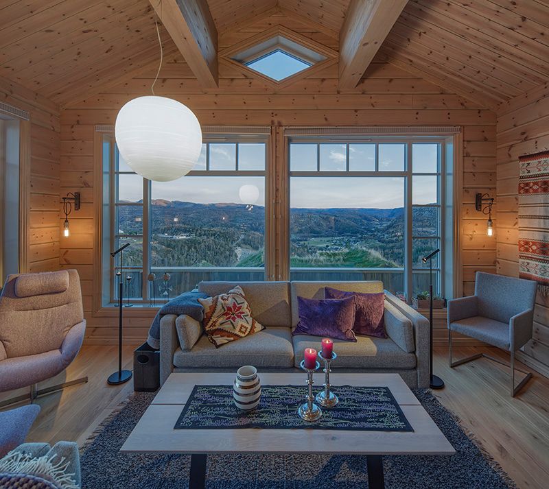 hytte med furuvegger og stort vindu med utsikt over fjellet