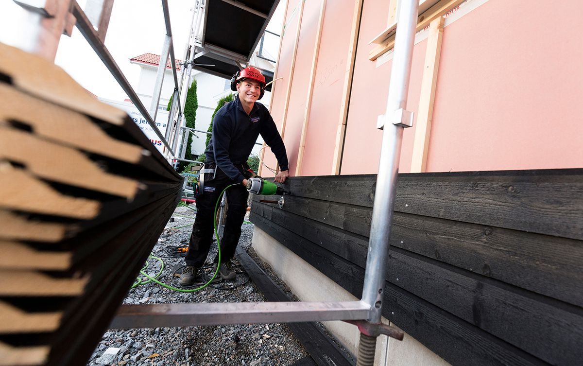 Snekker som monterer ny utvendig kledning på et hus