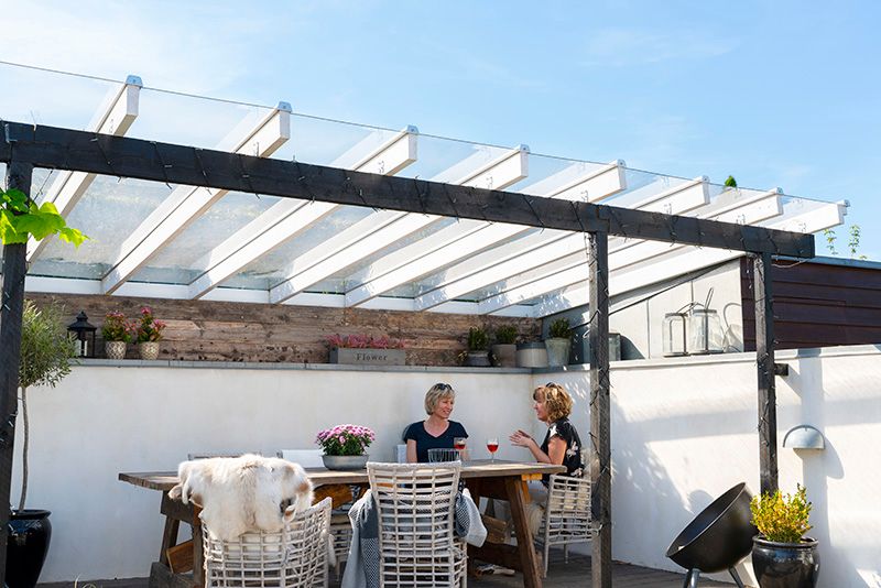 koselig uteplass med overbygget terrassetak. To kvinner spiser lunsj