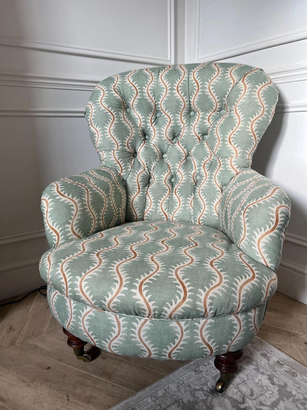 A button -backed armchair in green wavy patterned fabric with red accents