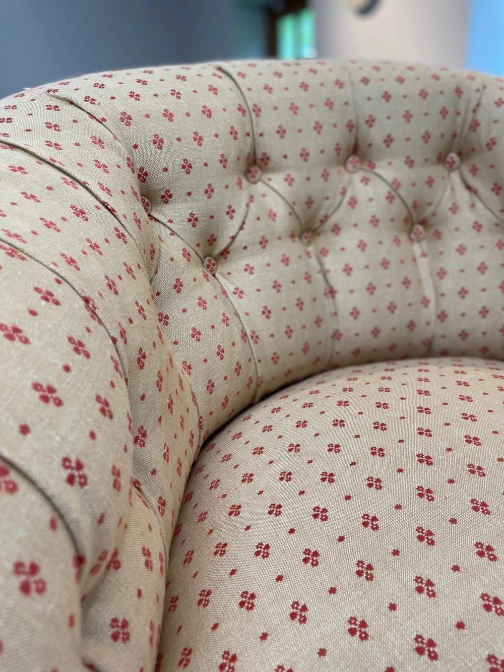 Close up detail of an low button backed armchair in red and beige pinstripe fabric