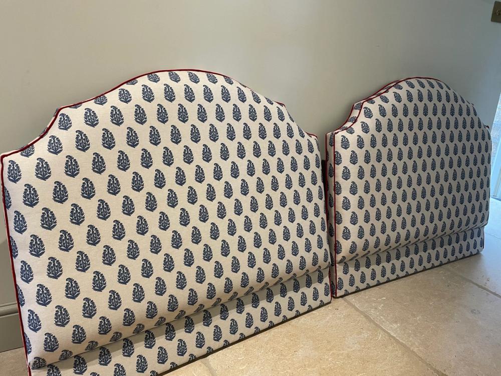Two matching bed heads with dark floral pattern motif on light background and dark red piping