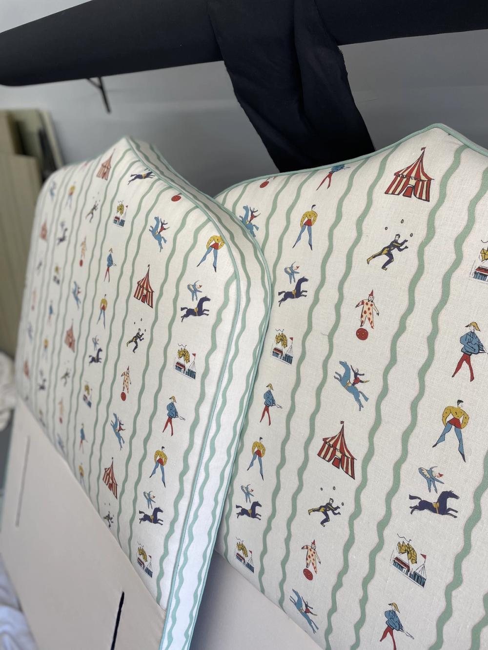 A pair of matching headboards upholstered in circus-themed pattern, viewed from the side
