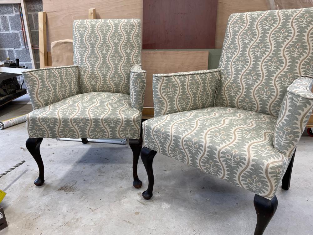 A pair of matching armchairs in light-green wavy pattern fabric with black Queen Anne style legs