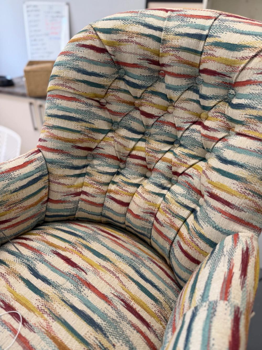 Close up detail of a button back armchair in multicoloured striped fabric