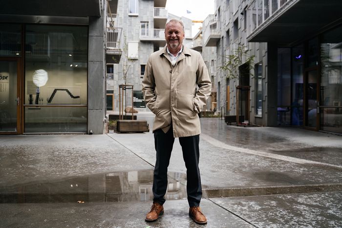 Byrådsleder Raymond Johansen står mellom boligbygg og smiler til kamera.