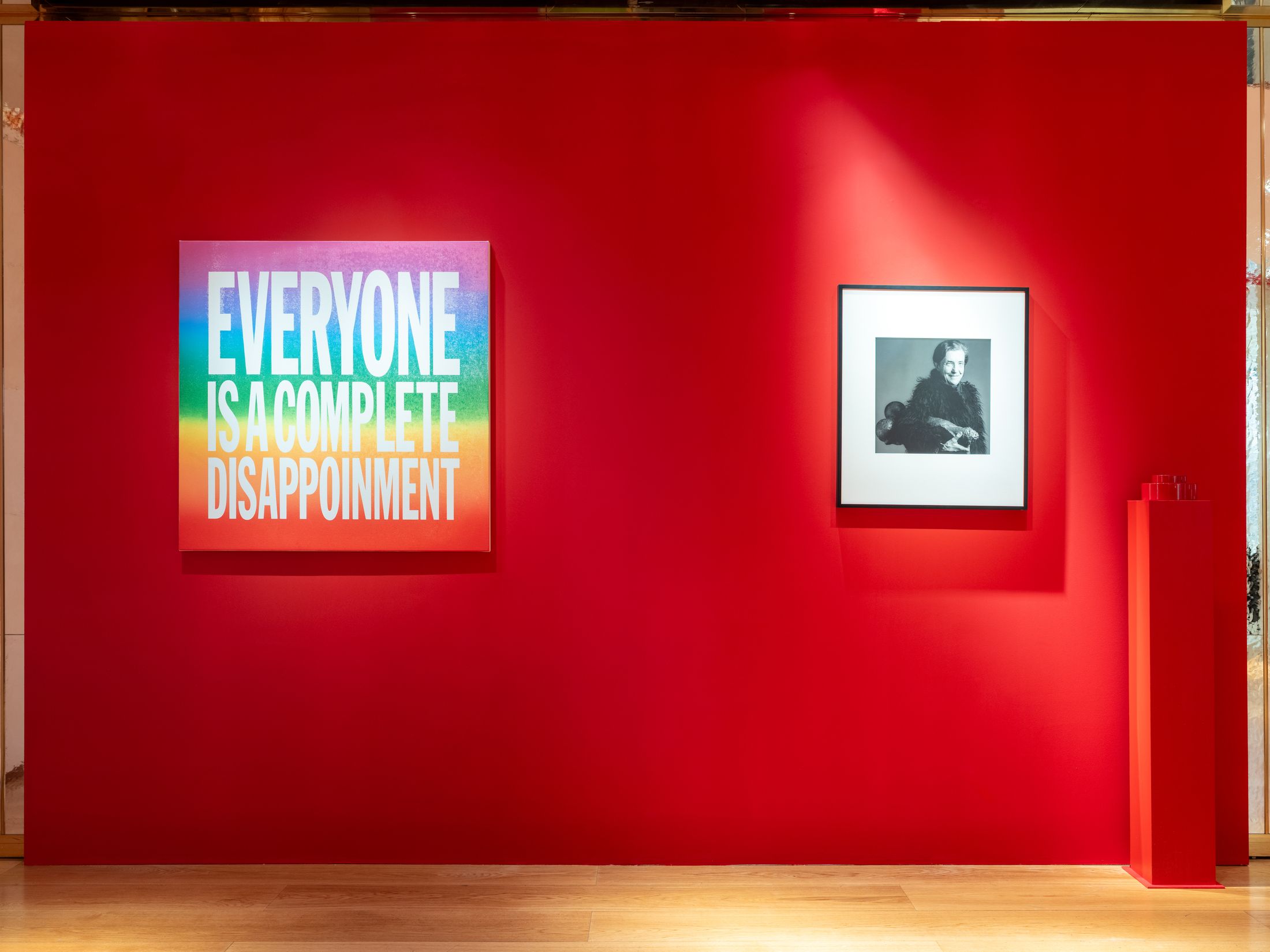 a multicoloured artwork and a photograph mounted on a red wall