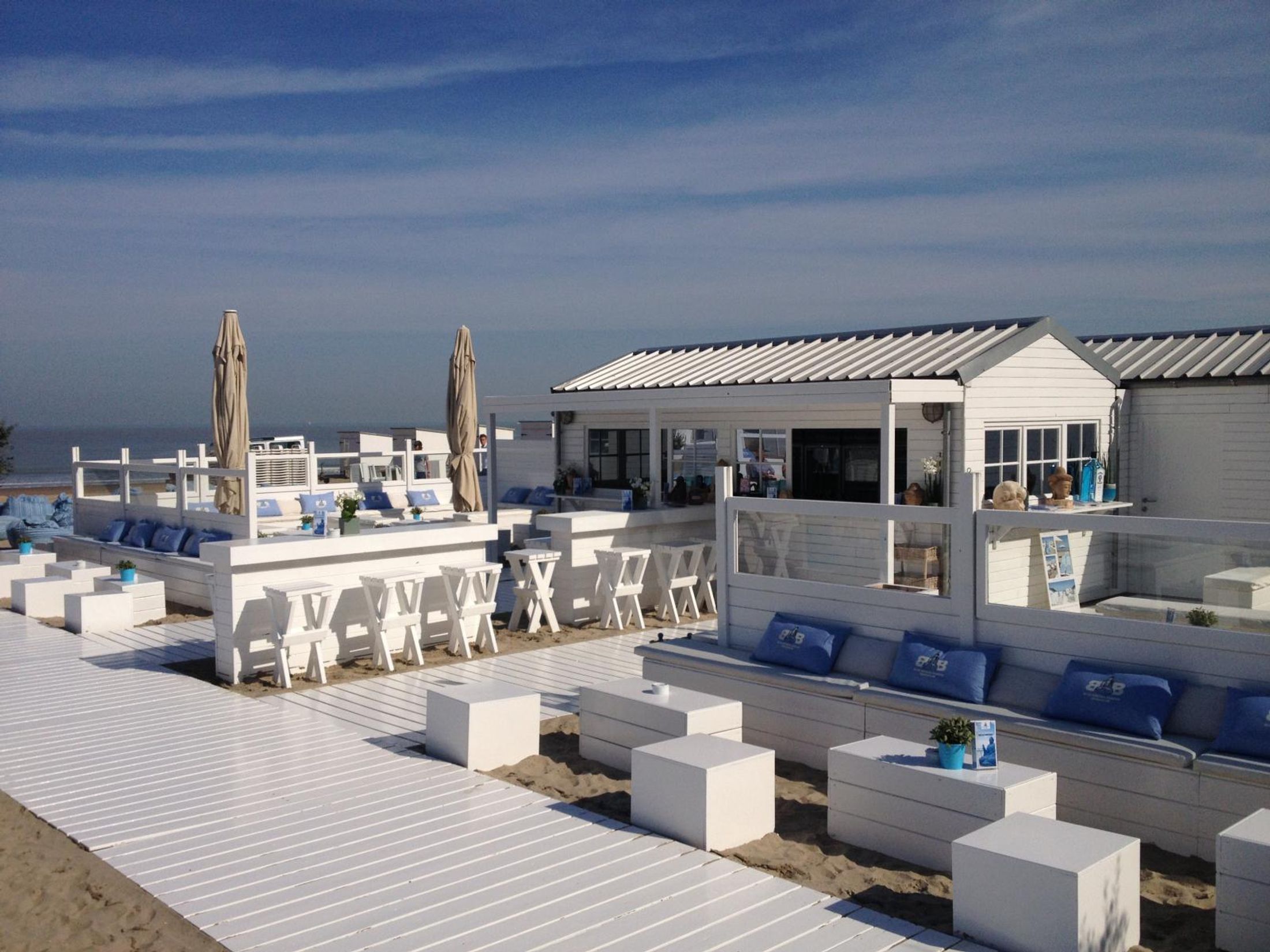 A beach with white decking and blue cushions