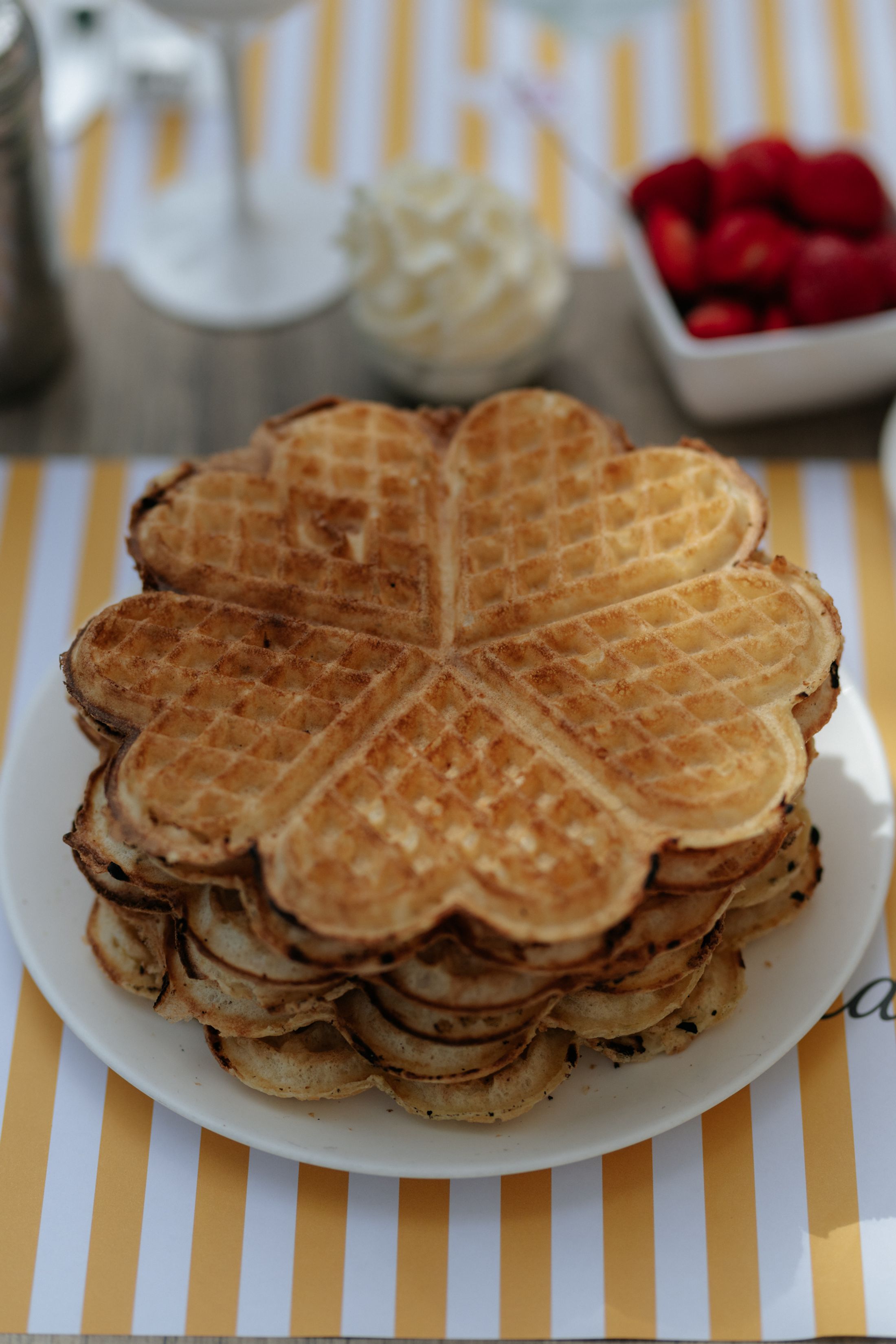 A plate of waffles with cream and strawberries