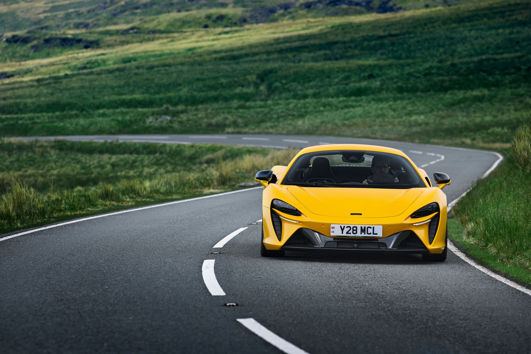 A yellow McLaren on a country road 