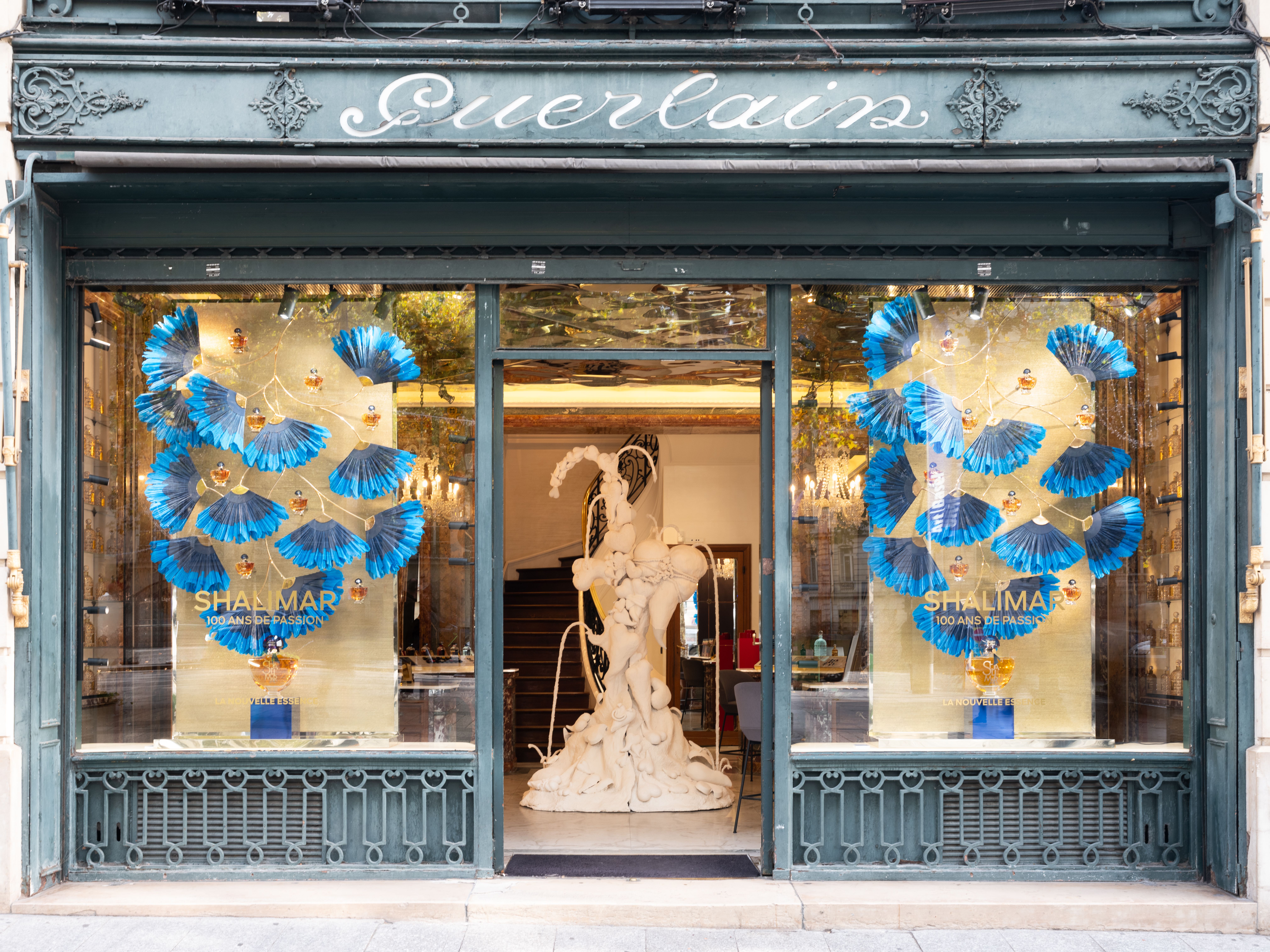 A shop window with a sculpture in the entrance and blue fans in the window