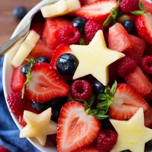 A festive fruit salad with blueberries, cut strawberries, and star-shaped pineapple pieces.