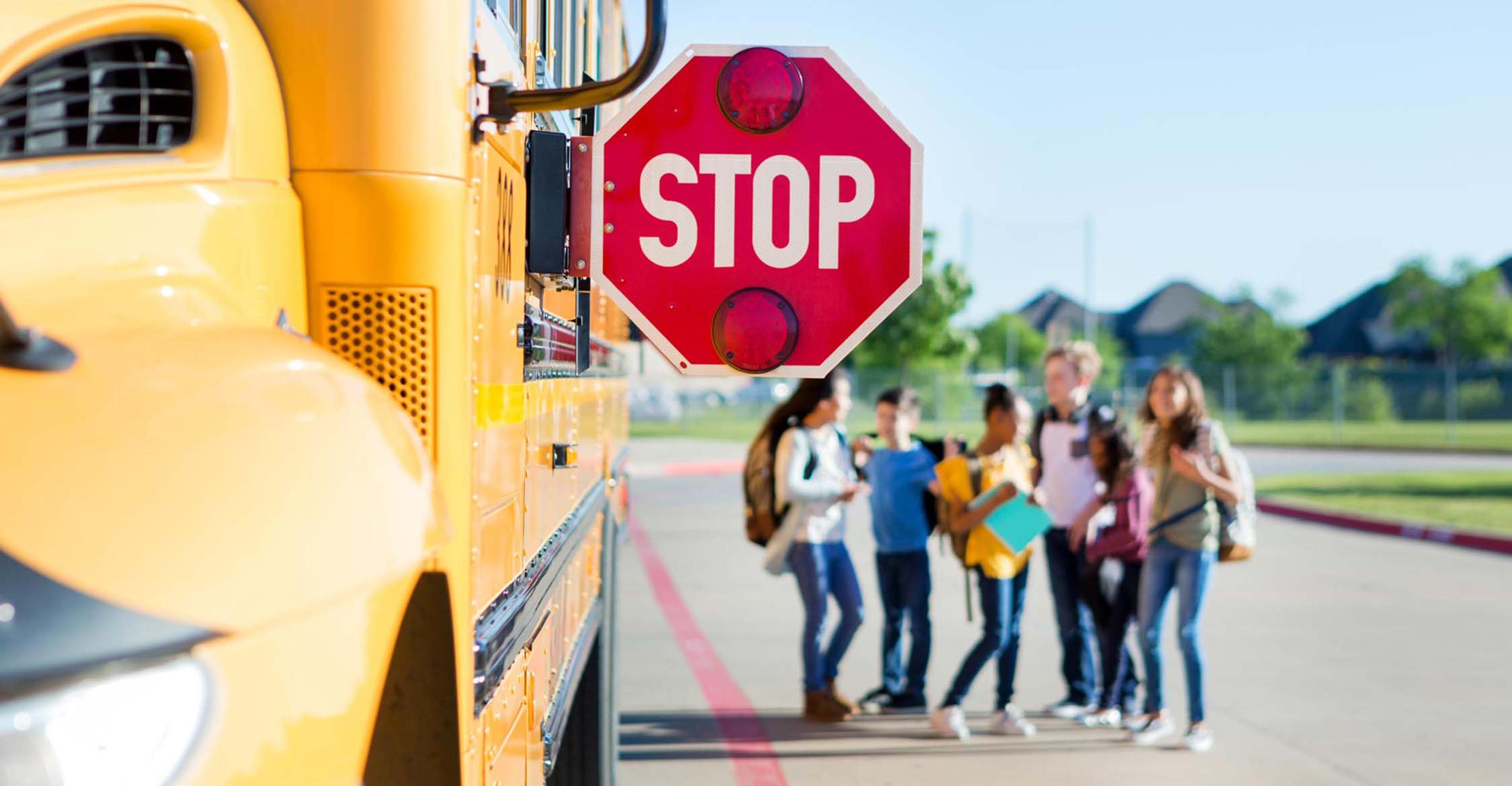 A group of kids waiting by a school bus