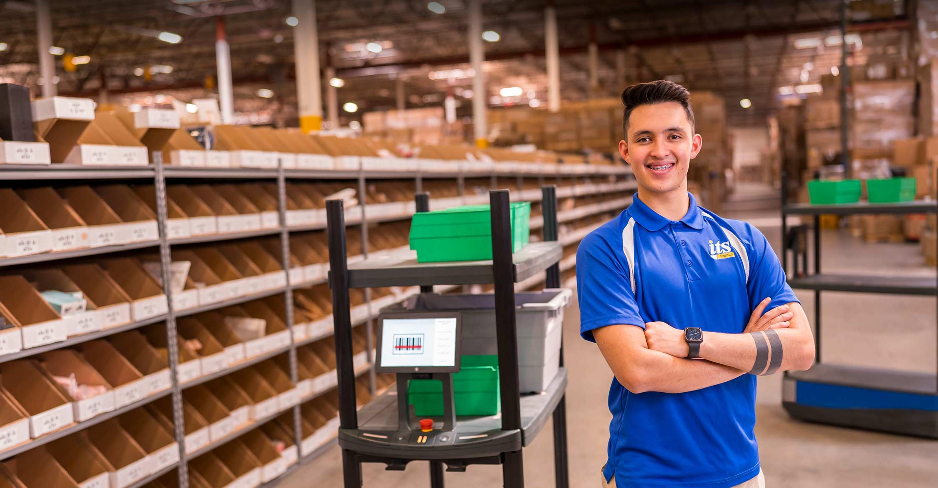 ITS team member smiling with arms crossed in warehouse