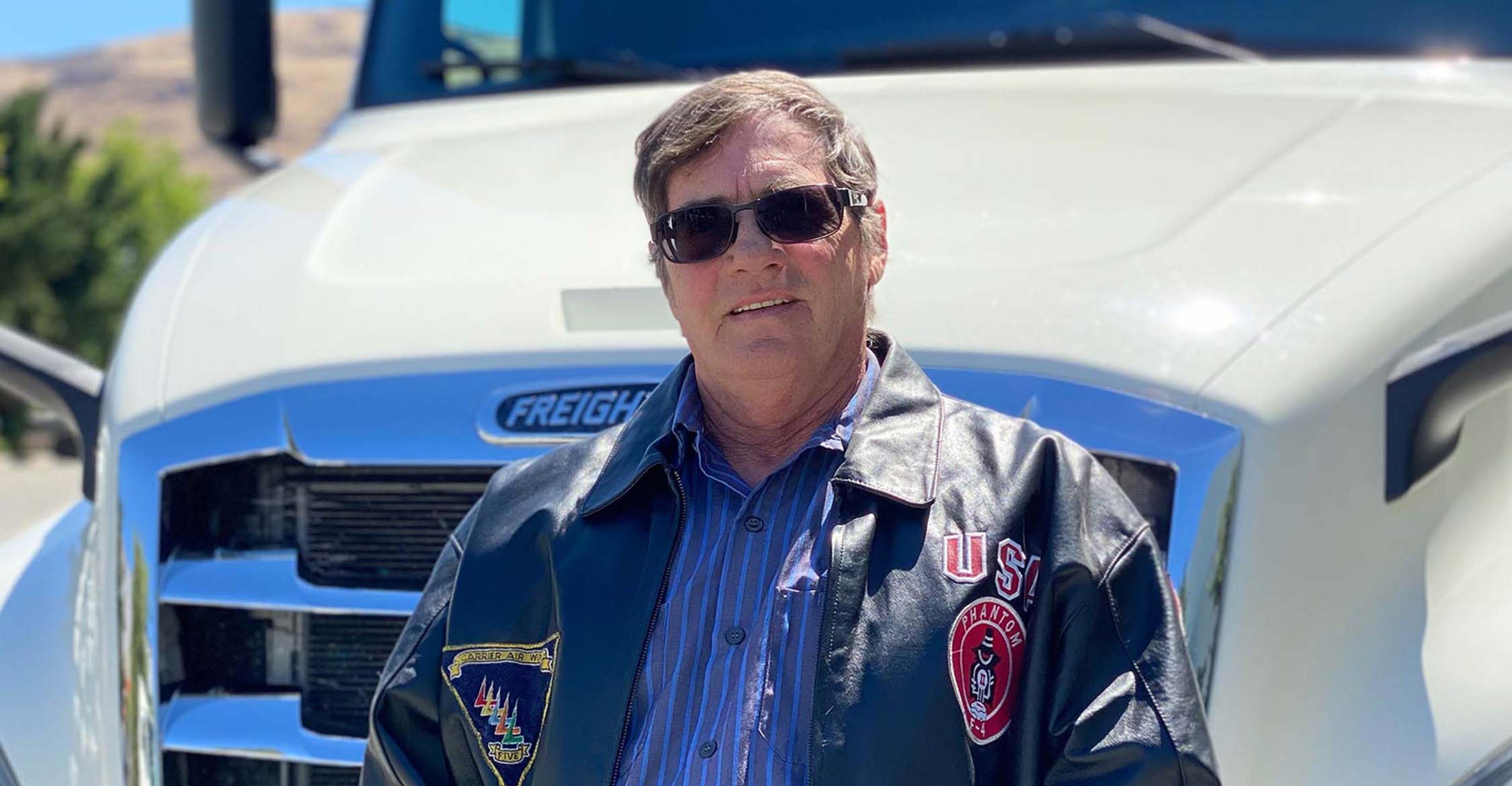 A veteran truck driver standing in front of a truck