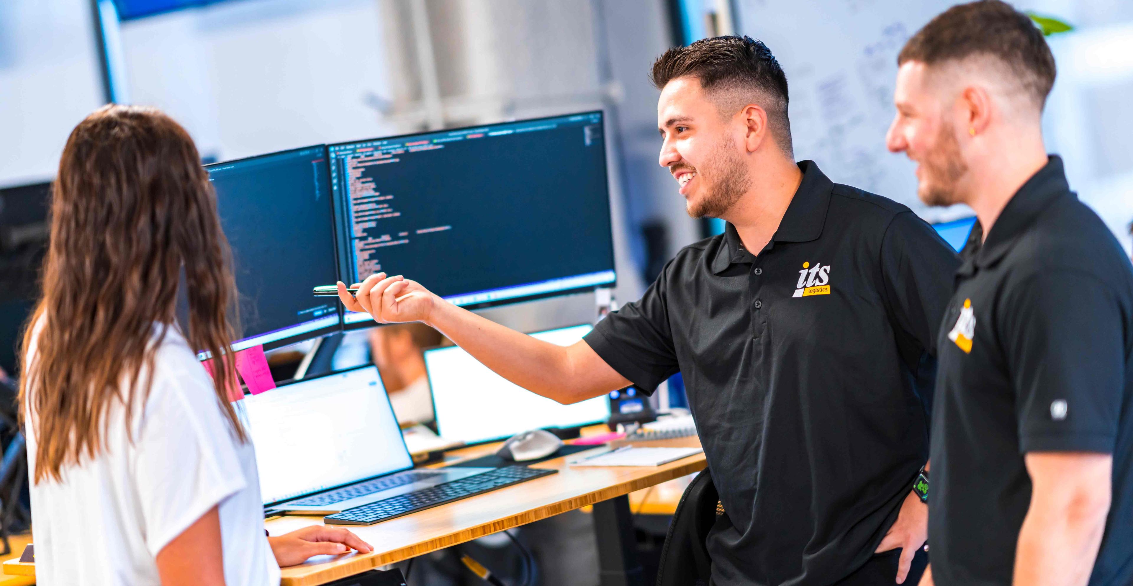 3 ITS employees looking at a computer screen.