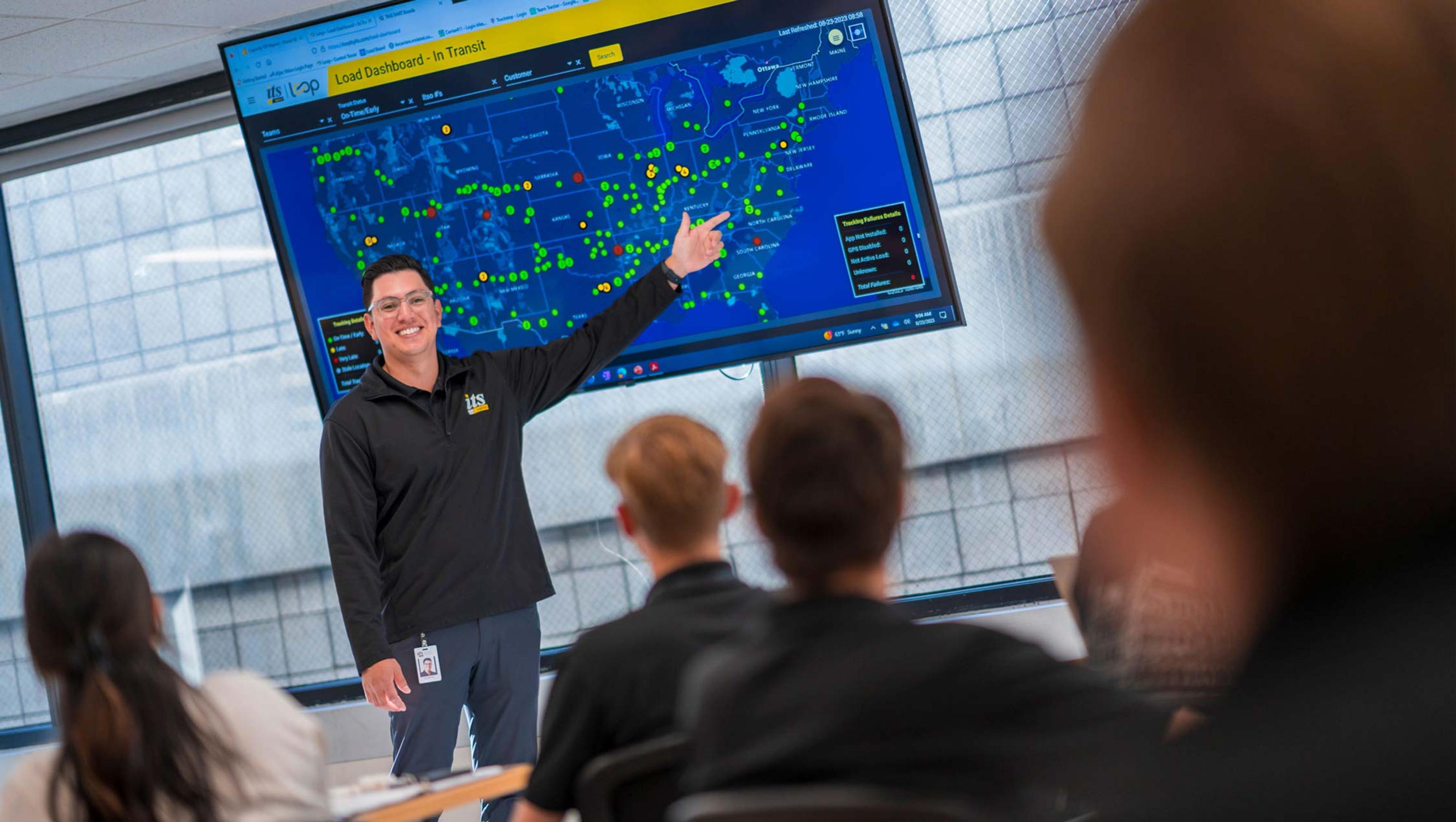 team leader pointing to map on tv