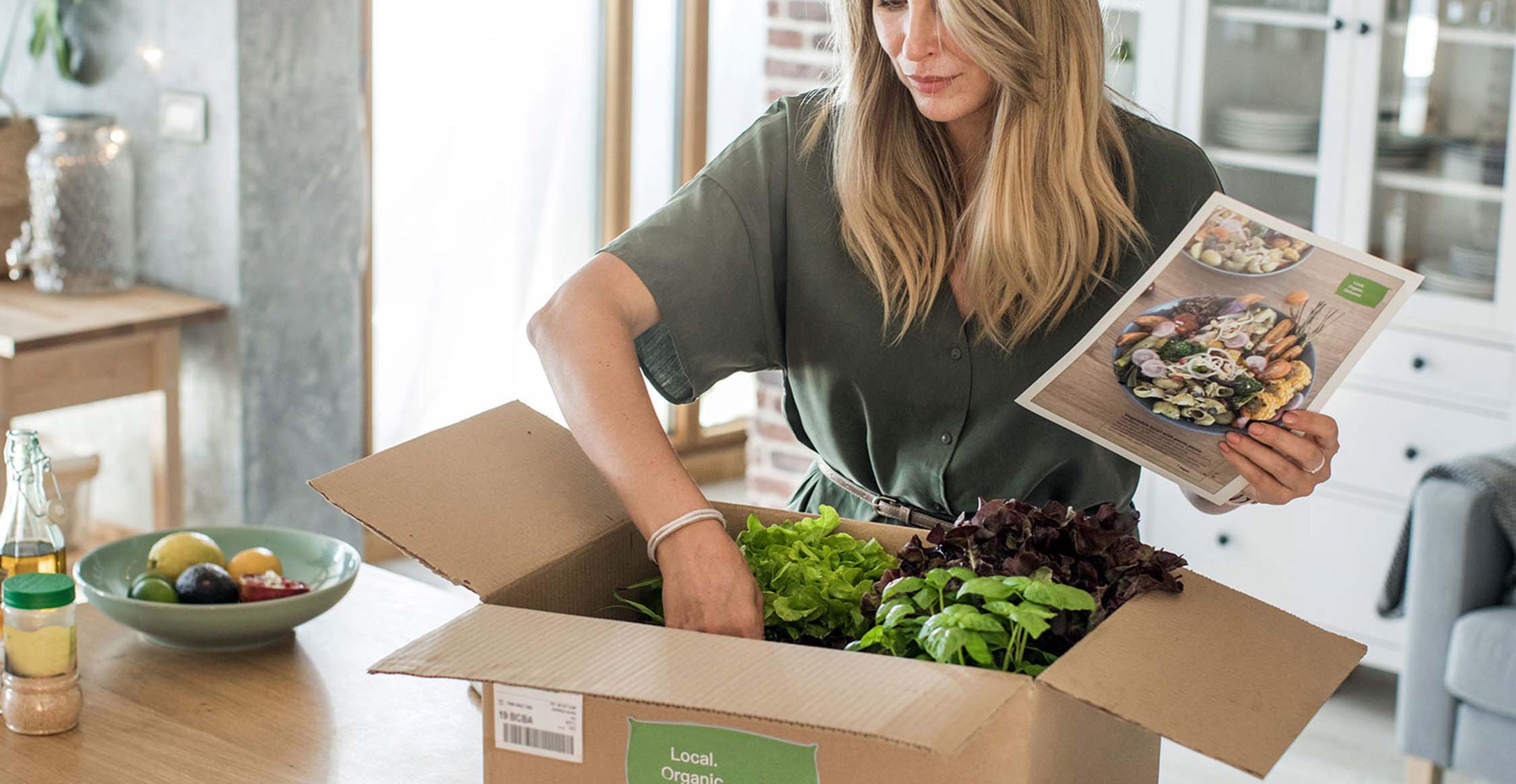 A person unboxing a box filled with produce