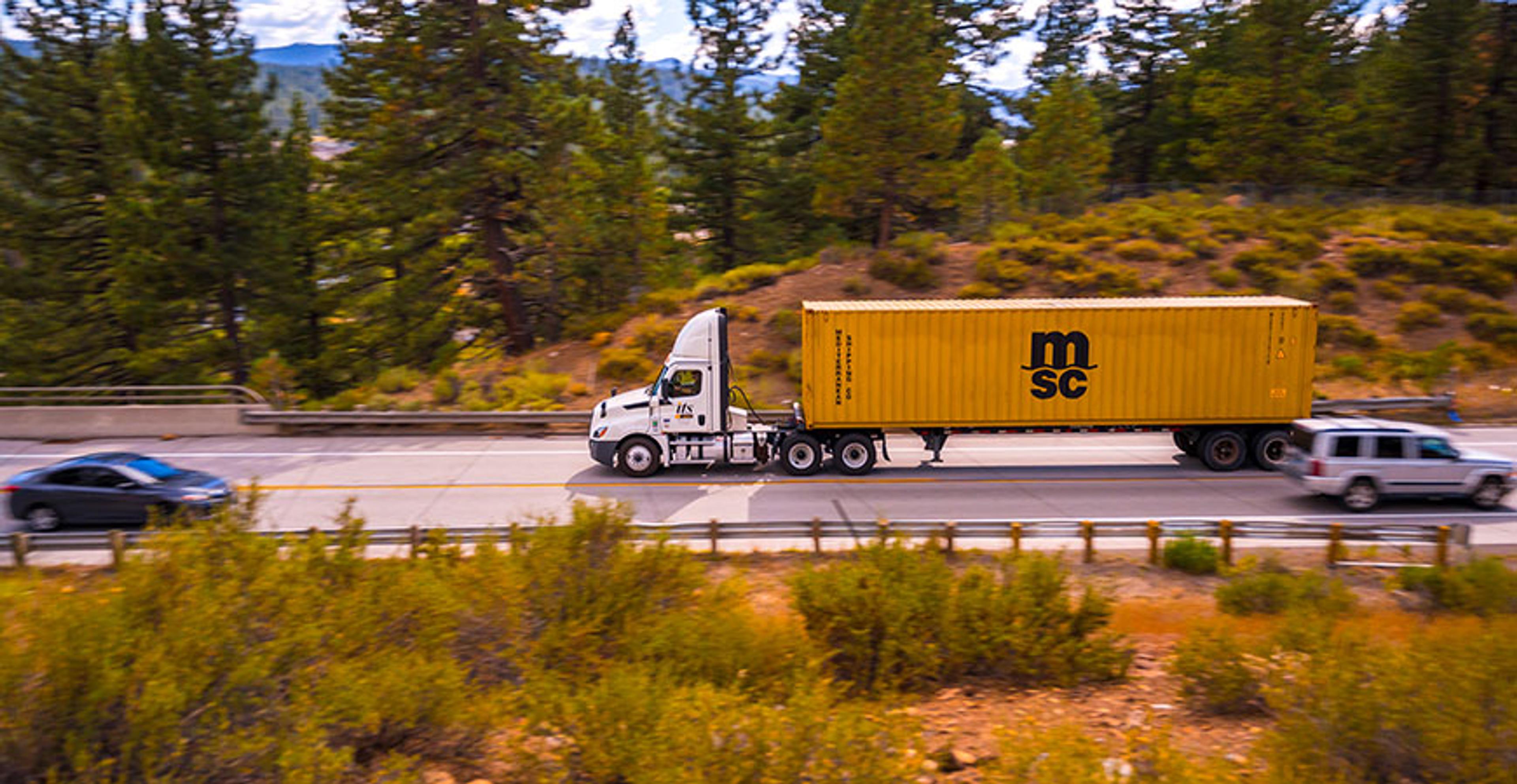 its truck driving down the freeway with connex container