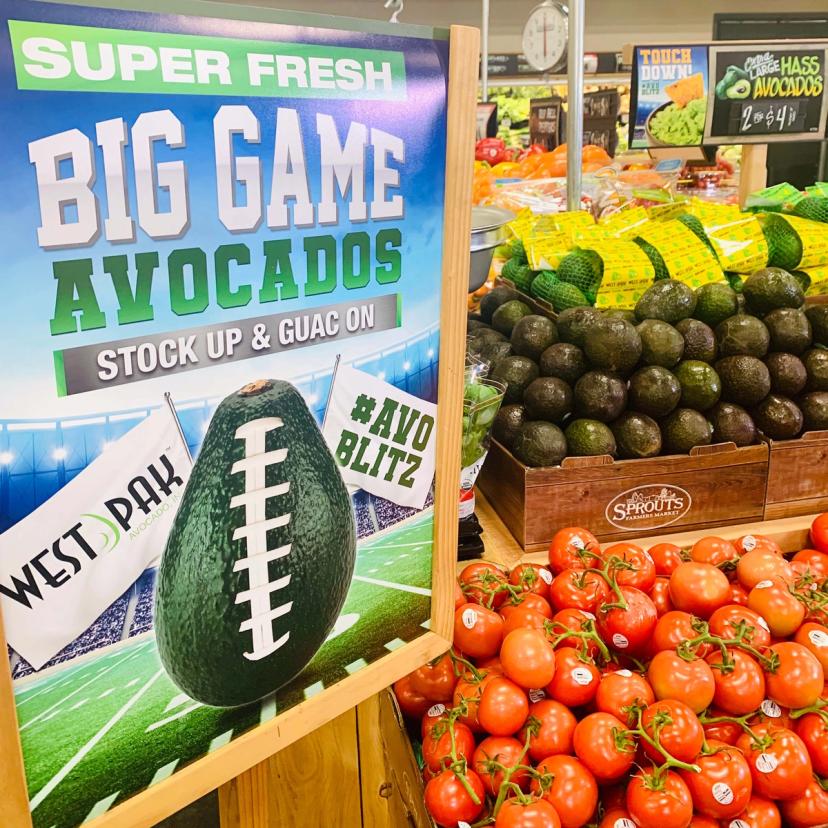 A grocery display of avocados featuring the Super Bowl