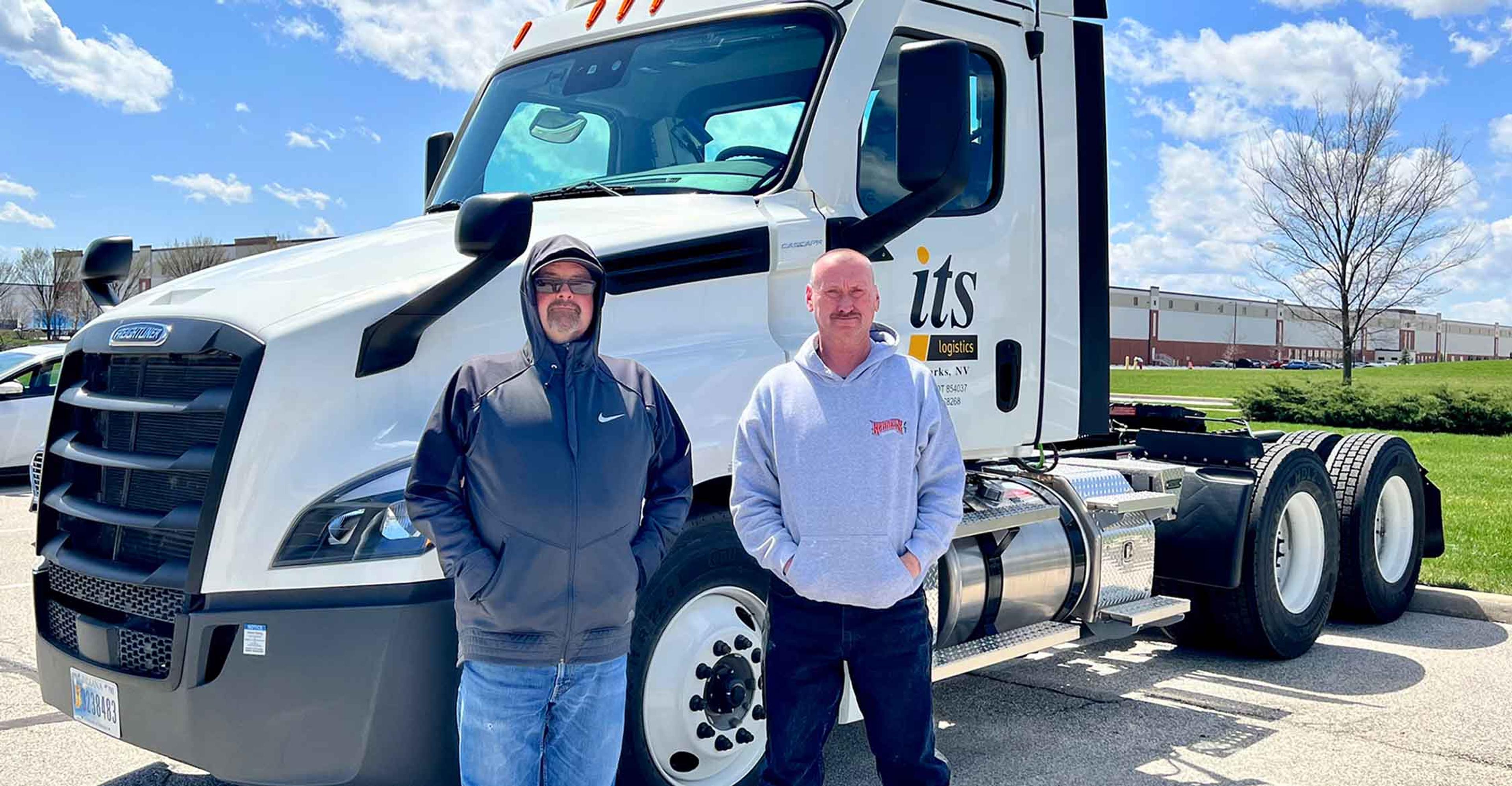 Two ITS drivers standing in front of a truck
