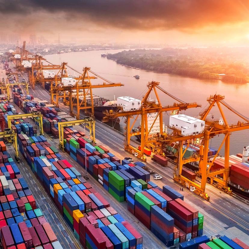 Aerial view of a ship being unloaded at a port with containers lined in the yard.