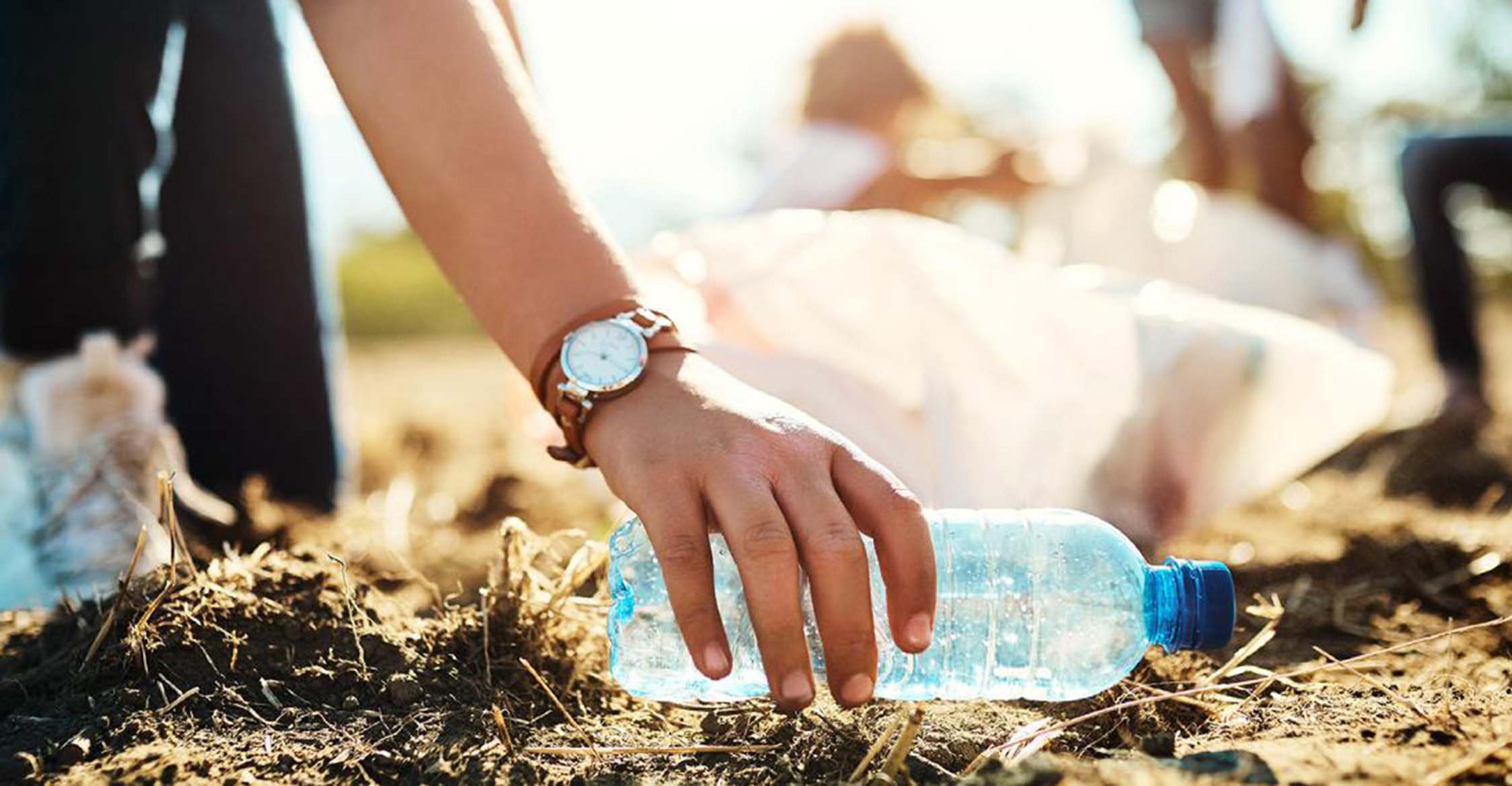 A person picking up a littered plastic bottle