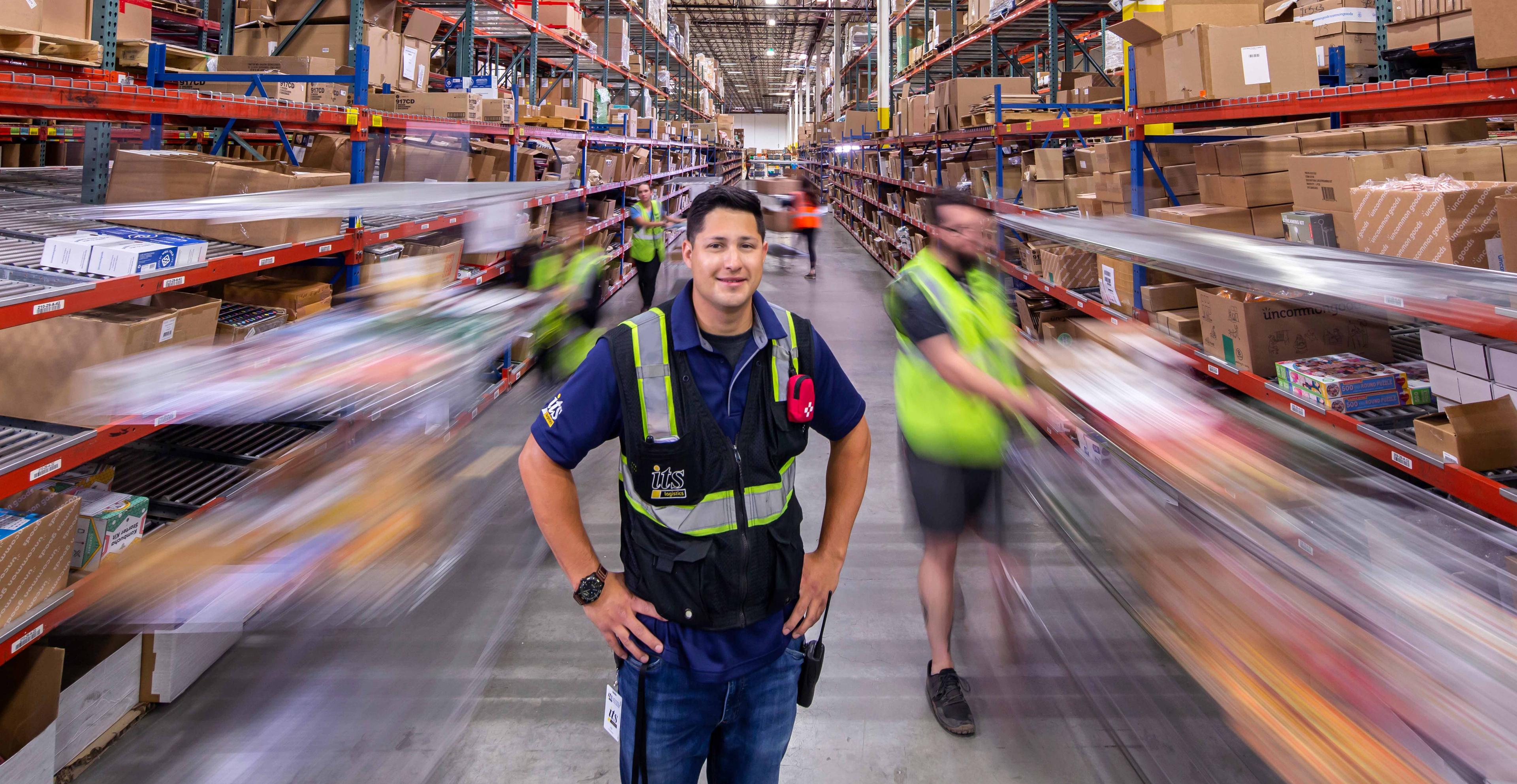 ITS Logistics team member featured in a bustling warehouse
