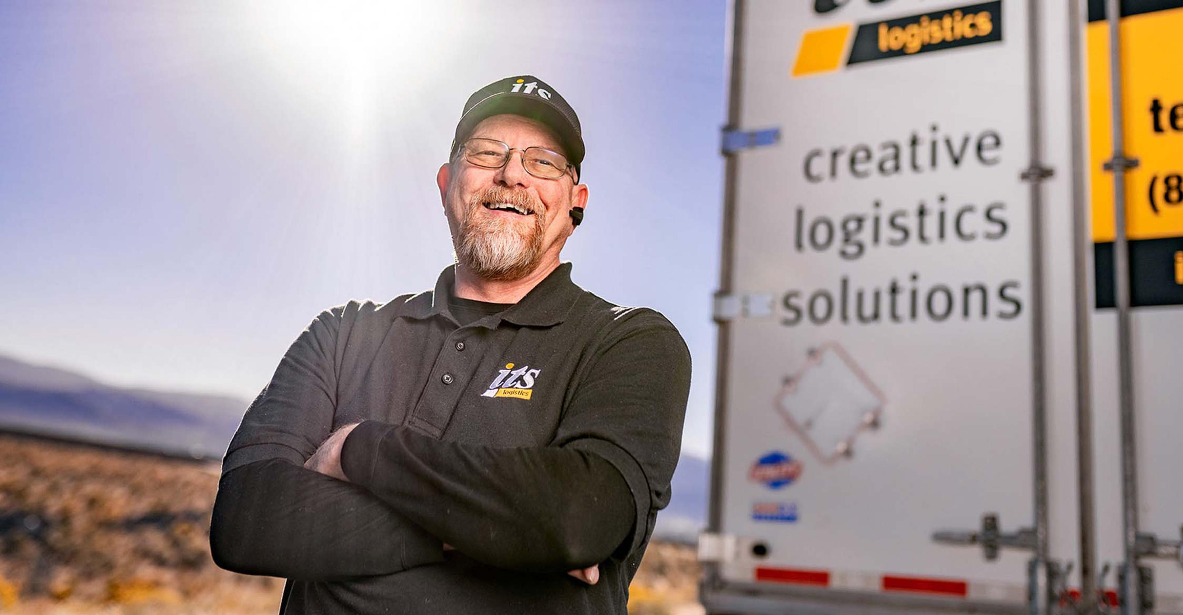 An ITS driver standing in front of the swing doors of a trailer