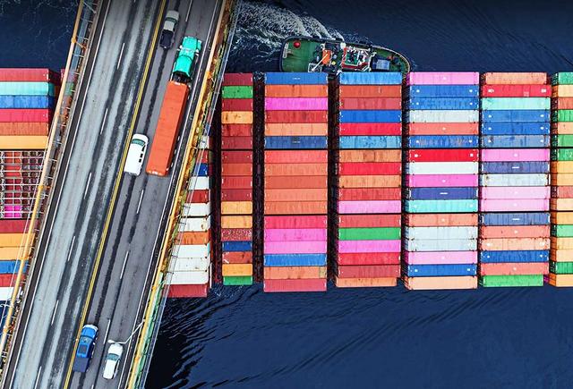 loaded cargo ship passing underneath bridge