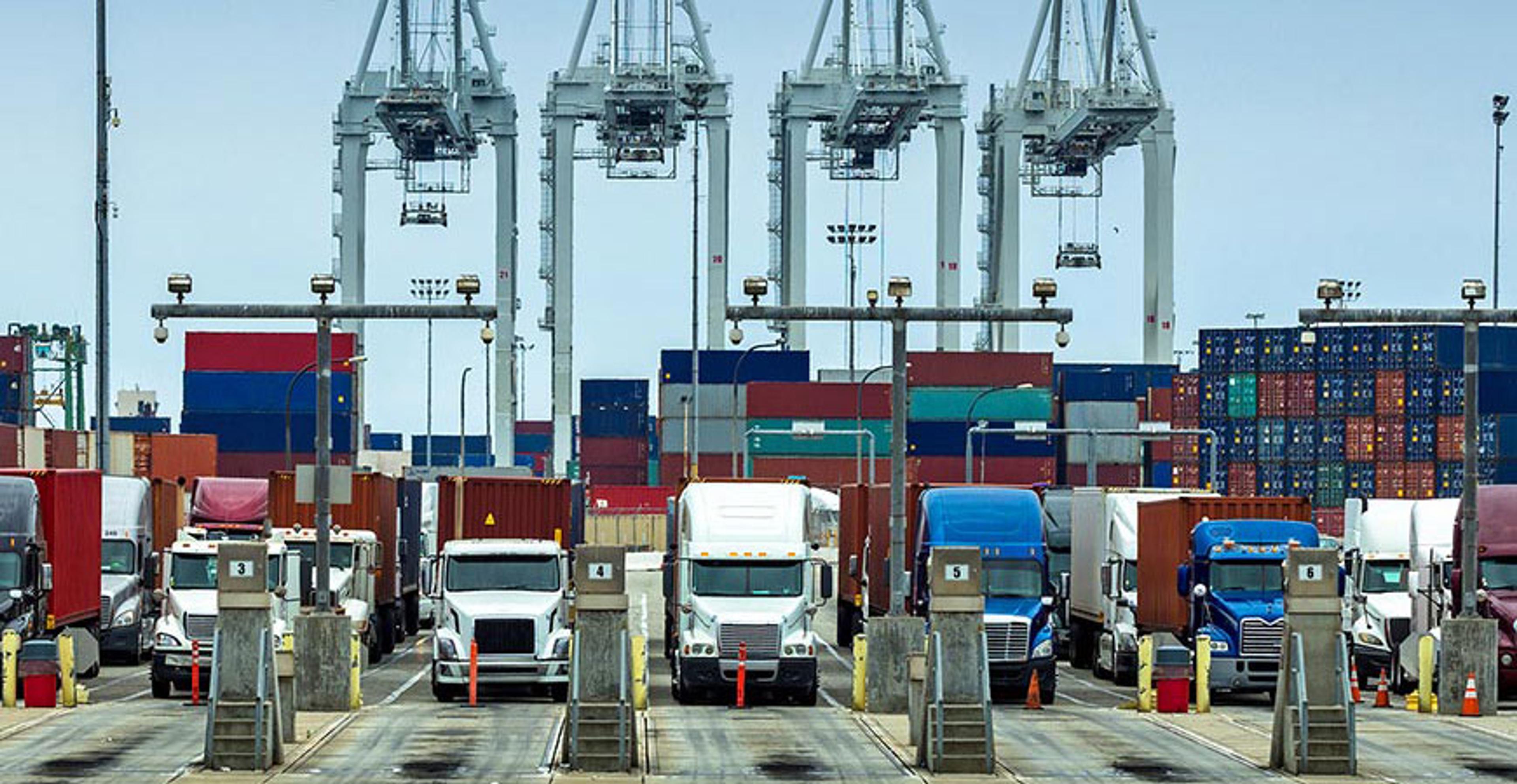 rows of semi trucks preparing to leave from the port with their loads